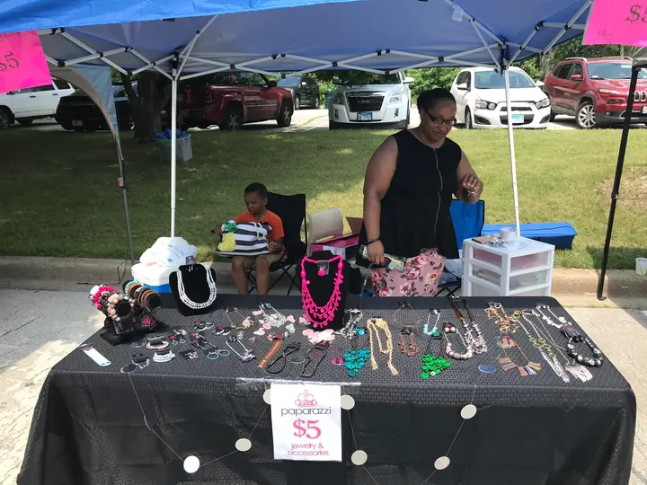 A vendor selling jewelry under a blue tent.