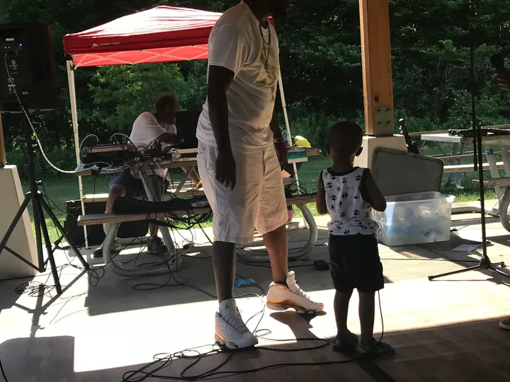 A man and a child dancing on the pavilion floor.