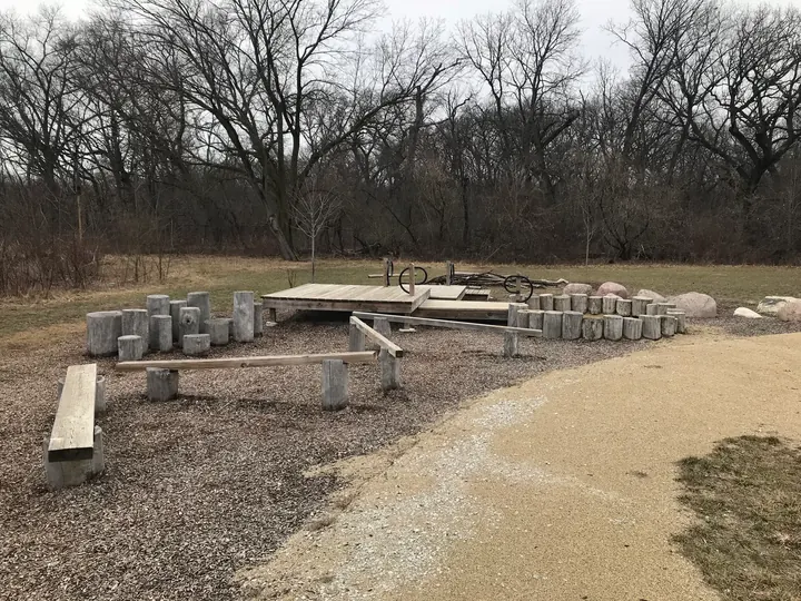 A gravel path past a campsite with a tent platform and log benches.