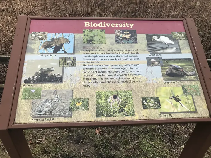 A biodiversity sign with photos of plants and animals.