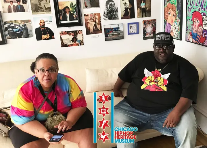 Two visitors on a couch in front of the photo wall.